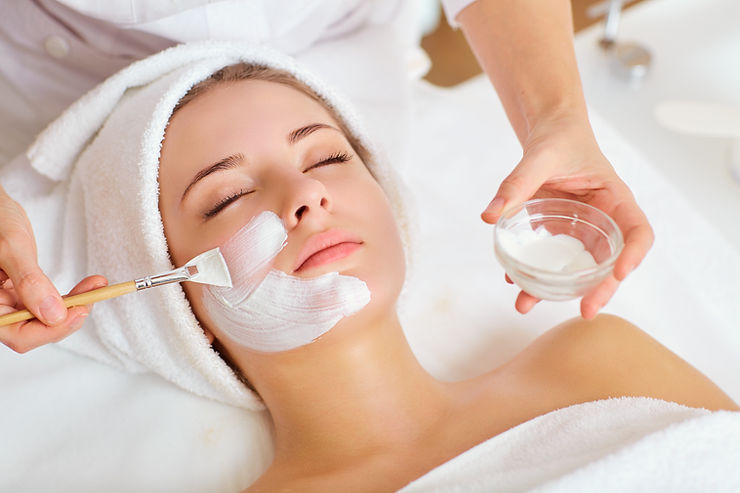Client receiving a facial mask application while reclining on a treatment bed